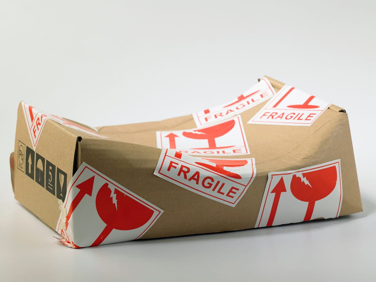 Cardboard box covered in fragile stickers, crushed in the middle