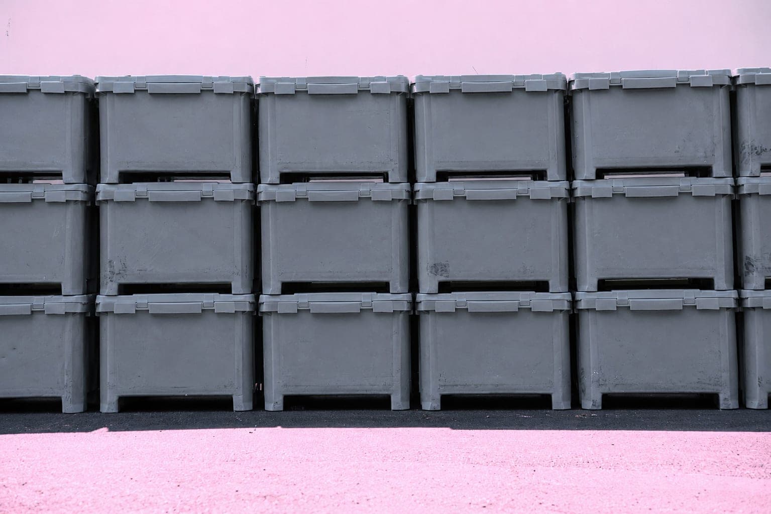 A wall of gray plastic crates stacked three high